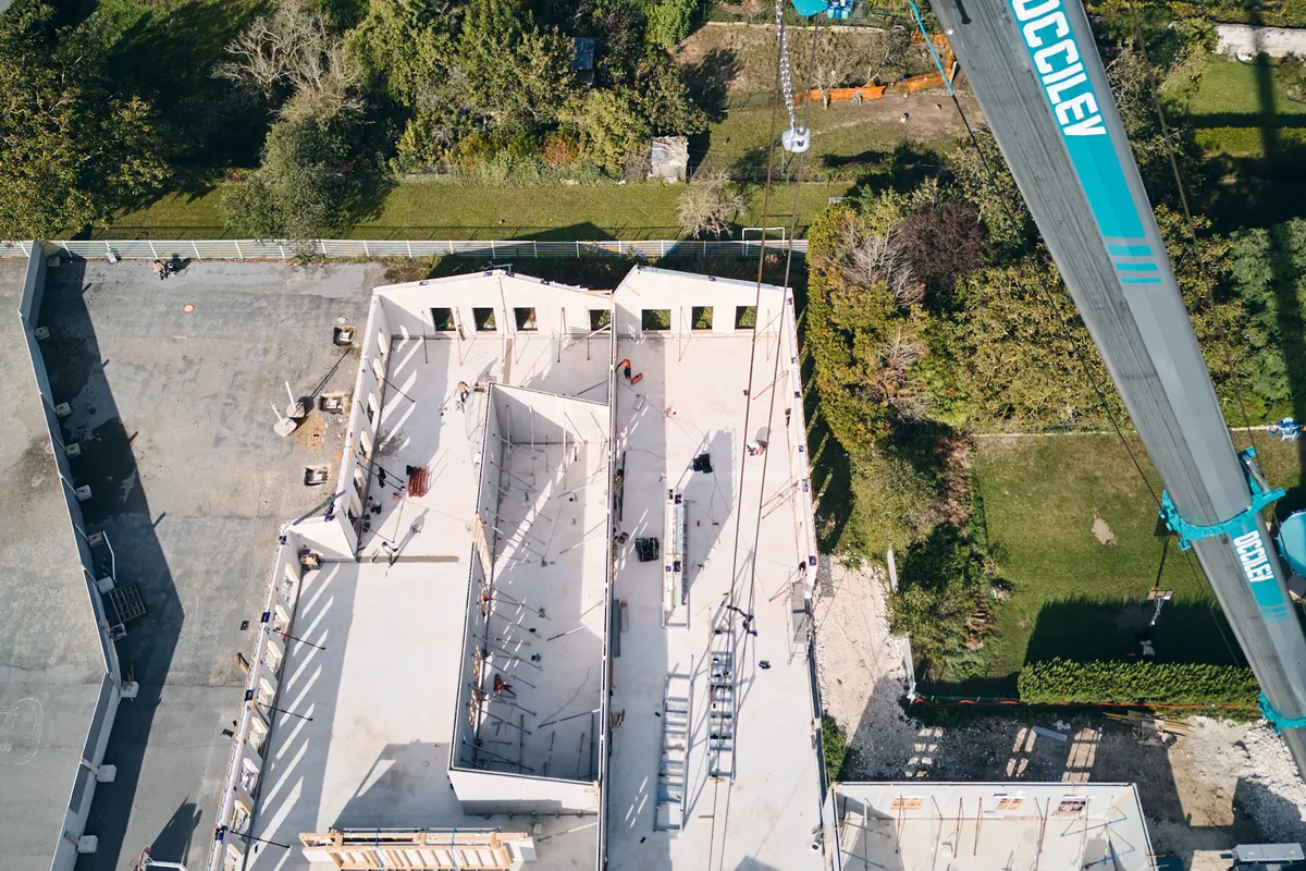 Vue drone du chantier en octobre 2023 : murs du réfectoire en cours de levage, grue sur place