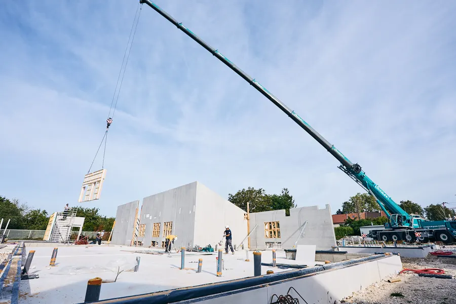 Grue mobile levant un mur au-dessus du chantier, ciel bleu