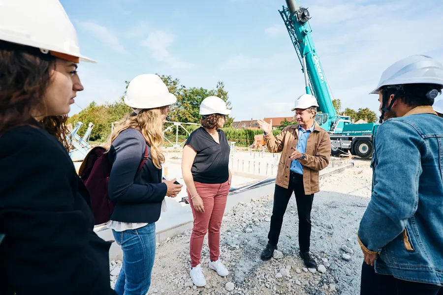 Visite de chantier en casques blancs, grue en arrière-plan