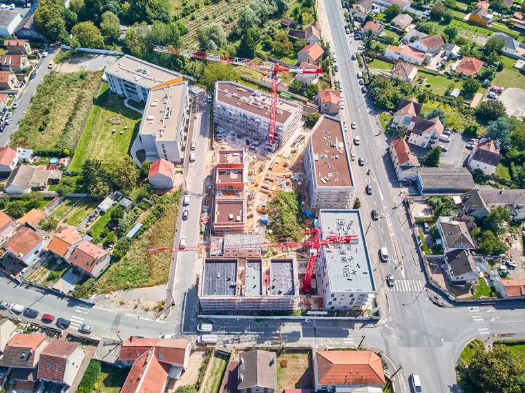 Vue plongeante au drone sur les immeubles en chantier et les flèches des grues