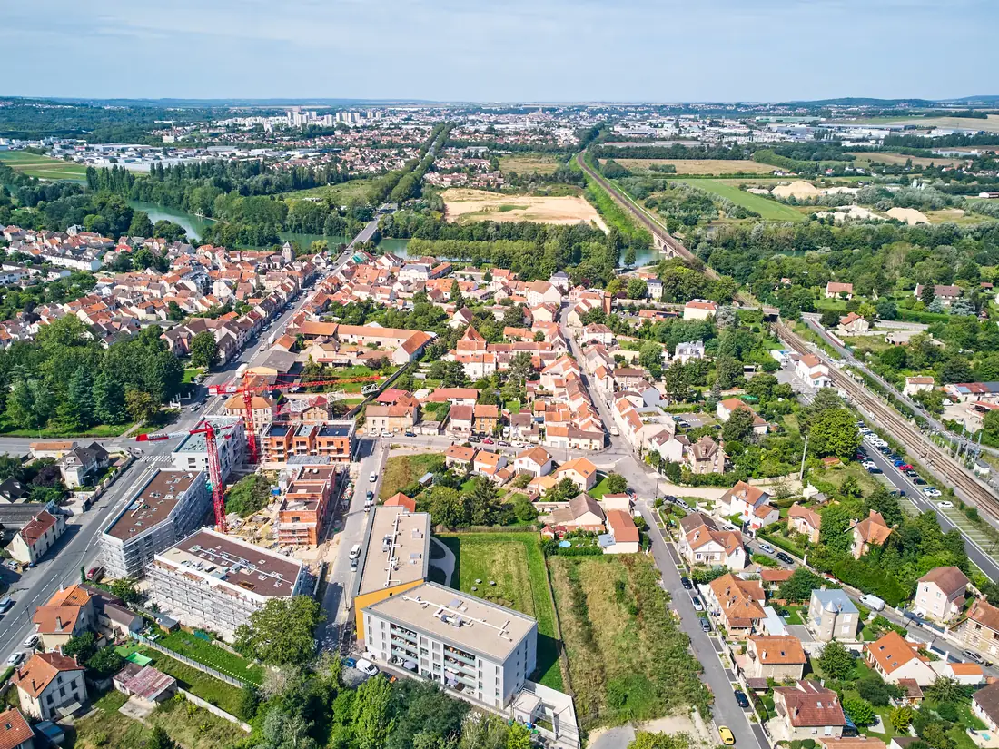 Vue aérienne lointaine du chantier au milieu des maisons, campagne en arrière-plan