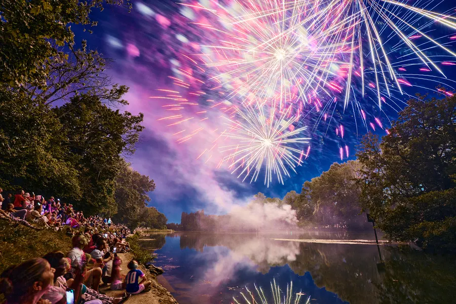 Le public sur la berge regarde le feu d'artifice tiré au-dessus de la Marne