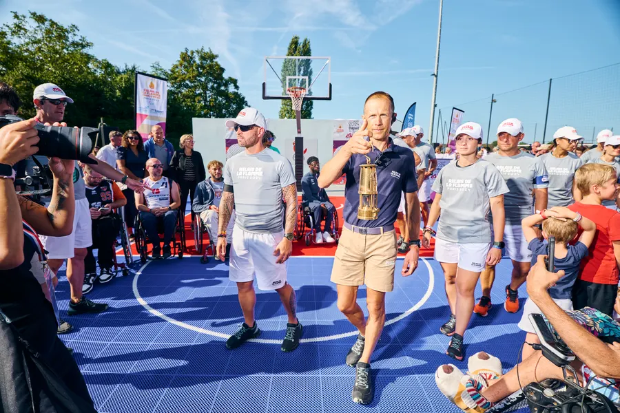 Le porteur de la lanterne de la flamme paralympique entouré des relayeurs sur le terrain de Trilport
